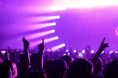 Konserin siluetleri parlak sahne ışıkları önünde kalabalık. Gece hayatı ve konser parti konsept.
