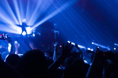 Konserin siluetleri parlak sahne ışıkları önünde kalabalık. Gece hayatı ve konser parti konsept.