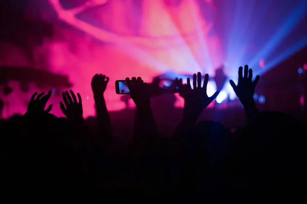 Siluetas de la multitud de conciertos frente a las luces del escenario brillantes. Vida nocturna y concepto de fiesta de concierto . — Foto de Stock