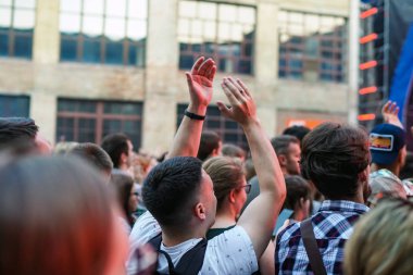 Konser kalabalık bir konser, insan siluetleri katılıyor mu görünür, arkadan aydınlatmalı sahne ışıkları tarafından. Yükseltilmiş elleri ve akıllı telefonlar orada burada görülebilir.