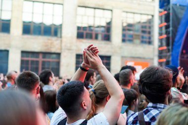 Konser kalabalık bir konser, insan siluetleri katılıyor mu görünür, arkadan aydınlatmalı sahne ışıkları tarafından. Yükseltilmiş elleri ve akıllı telefonlar orada burada görülebilir.