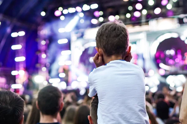 子供は、屋外のロックミュージックコンサートで彼らと手をつないで彼女の両親の肩に楽しみを持っています — ストック写真