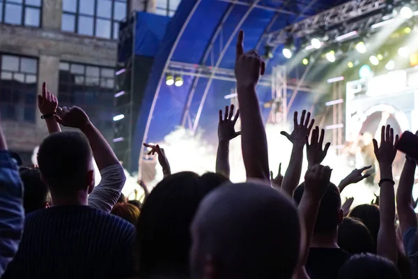 Konser kalabalık bir konser, insan siluetleri katılıyor mu görünür, arkadan aydınlatmalı sahne ışıkları tarafından. Yükseltilmiş elleri ve akıllı telefonlar orada burada görülebilir.