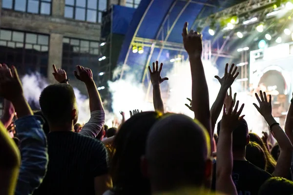 Konser kalabalık bir konser, insan siluetleri katılıyor mu görünür, arkadan aydınlatmalı sahne ışıkları tarafından. Yükseltilmiş elleri ve akıllı telefonlar orada burada görülebilir.
