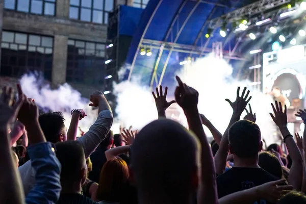 Konser kalabalık bir konser, insan siluetleri katılıyor mu görünür, arkadan aydınlatmalı sahne ışıkları tarafından. Yükseltilmiş elleri ve akıllı telefonlar orada burada görülebilir.