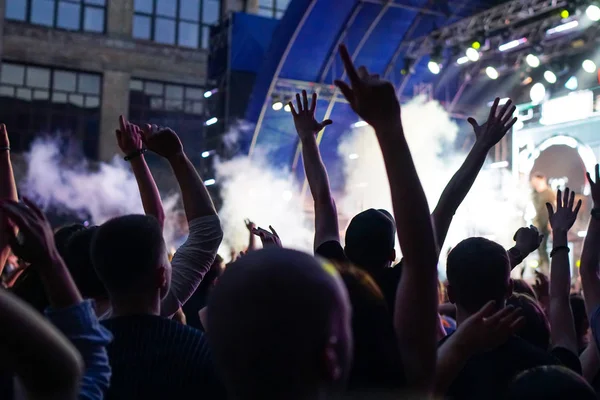 Konser kalabalık bir konser, insan siluetleri katılıyor mu görünür, arkadan aydınlatmalı sahne ışıkları tarafından. Yükseltilmiş elleri ve akıllı telefonlar orada burada görülebilir.