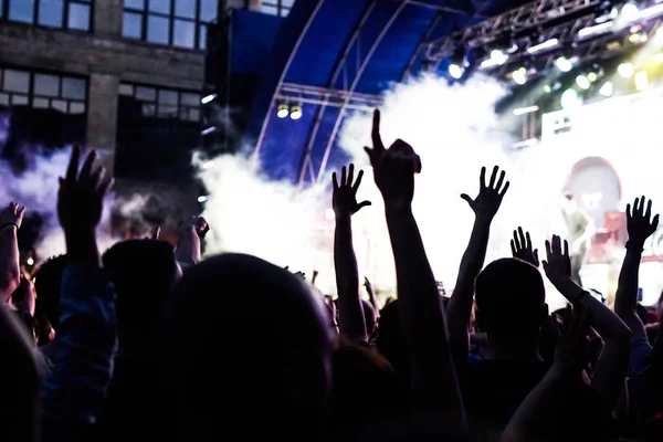 Konser kalabalık bir konser, insan siluetleri katılıyor mu görünür, arkadan aydınlatmalı sahne ışıkları tarafından. Yükseltilmiş elleri ve akıllı telefonlar orada burada görülebilir.