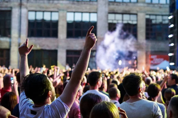 Konser kalabalık bir konser, insan siluetleri katılıyor mu görünür, arkadan aydınlatmalı sahne ışıkları tarafından. Yükseltilmiş elleri ve akıllı telefonlar orada burada görülebilir.