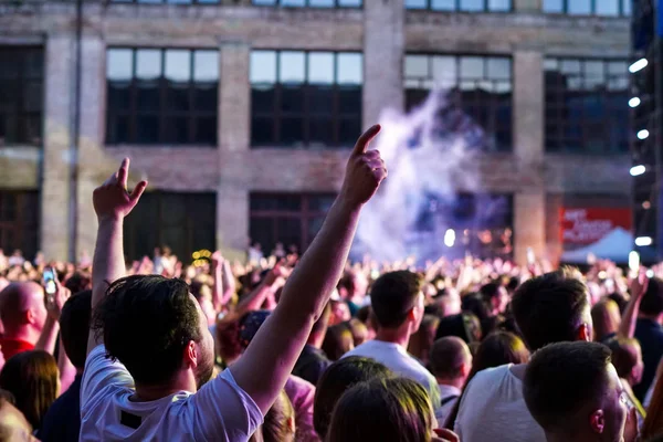 Konser kalabalık bir konser, insan siluetleri katılıyor mu görünür, arkadan aydınlatmalı sahne ışıkları tarafından. Yükseltilmiş elleri ve akıllı telefonlar orada burada görülebilir.