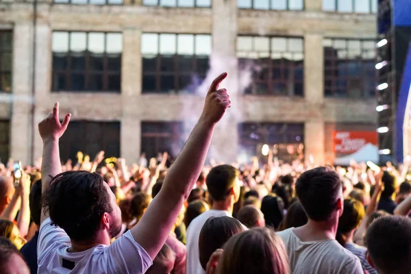 Konser kalabalık bir konser, insan siluetleri katılıyor mu görünür, arkadan aydınlatmalı sahne ışıkları tarafından. Yükseltilmiş elleri ve akıllı telefonlar orada burada görülebilir.