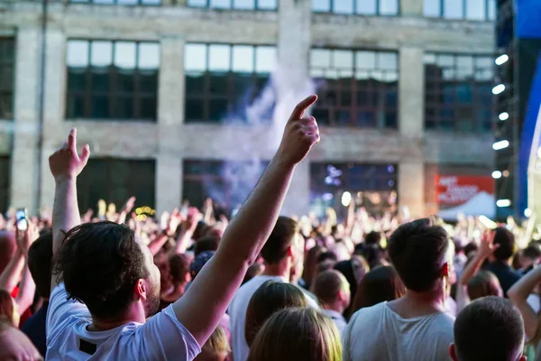 Konser kalabalık bir konser, insan siluetleri katılıyor mu görünür, arkadan aydınlatmalı sahne ışıkları tarafından. Yükseltilmiş elleri ve akıllı telefonlar orada burada görülebilir.