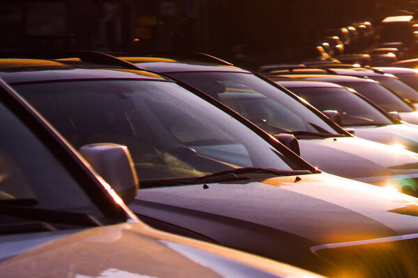Несколько машин припарковано на стоянке против восхода солнца
