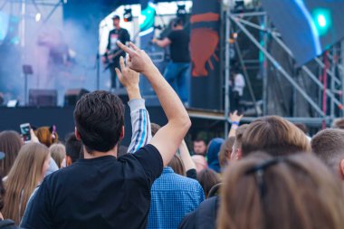 Bir müzik festivalinde seyirciler ellerini kaldırdı ve sahnenin üstünden ışıklar süzülüyor..