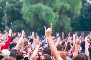 Bir müzik festivalinde seyirciler ellerini kaldırdı ve sahnenin üstünden ışıklar süzülüyor..