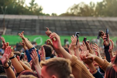Bir müzik festivalinde seyirciler ellerini kaldırdı ve sahnenin üstünden ışıklar süzülüyor..