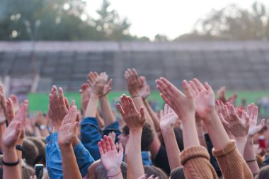 Bir müzik festivalinde seyirciler ellerini kaldırdı ve sahnenin üstünden ışıklar süzülüyor..
