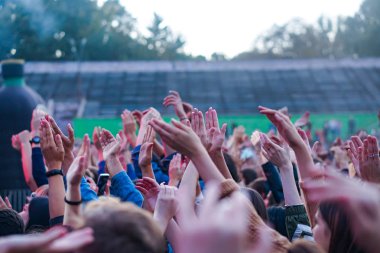 Bir müzik festivalinde seyirciler ellerini kaldırdı ve sahnenin üstünden ışıklar süzülüyor..