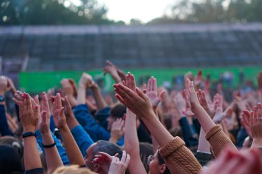 Bir müzik festivalinde seyirciler ellerini kaldırdı ve sahnenin üstünden ışıklar süzülüyor..