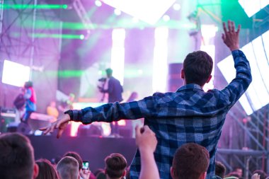 Siluetleri insanların bir konserde. Pop konseri. Rock grubu. Adam eliyle bir keçi var. Sahne Alanı'ndaki parlak ışık.