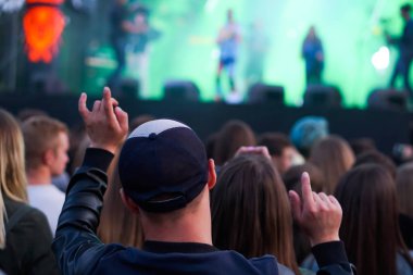Siluetleri insanların bir konserde. Pop konseri. Rock grubu. Adam eliyle bir keçi var. Sahne Alanı'ndaki parlak ışık.