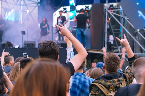 音楽祭で手を挙げ、舞台上から光が流れ落ちる観客. — ストック写真