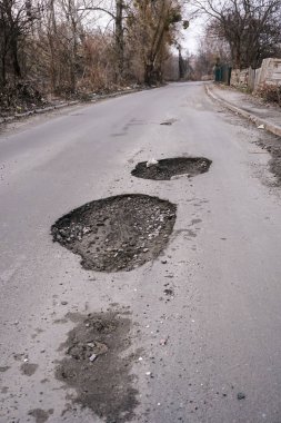 Asfalt karayolu üzerinde taşlarla büyük çukur