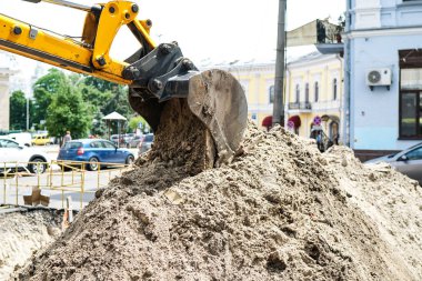 Taş ocağındaki yol şantiyesindeki inşaat makineleri toprak kazıyor ve kum döküyor.