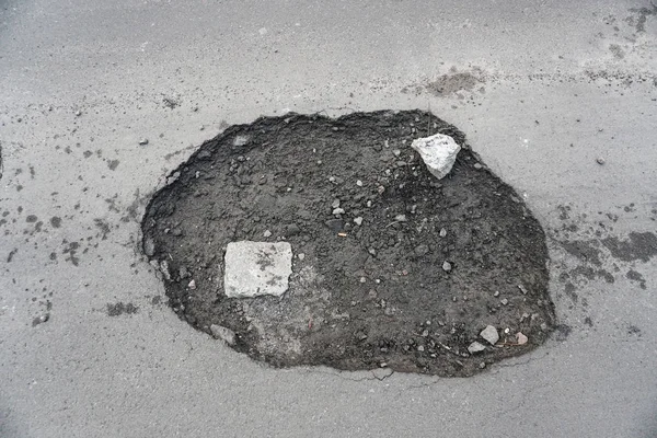 Große Grube mit Steinen auf der Asphaltstraße — Stockfoto