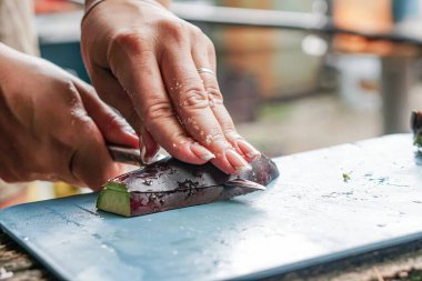 Kız sokakta ve yaz mutfağında patlıcan kesiyor.