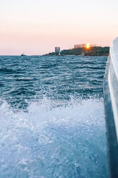 Waves on the blue sea behind the water of a speedboat with bright sun, sunny sunset — Stock Photo, Image