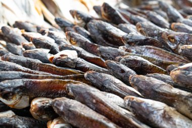 Farklı türde kurumuş balıklar sokak pazarında yatıyor.