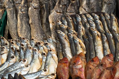 Farklı türde kurumuş balıklar sokak pazarında yatıyor.