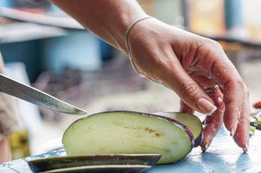 Kız sokakta ve yaz mutfağında patlıcan kesiyor.