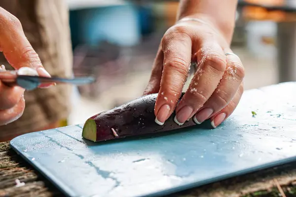 stock image the girl cuts the eggplant on the street, and in the summer kitchen