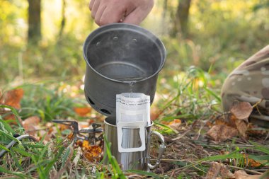 Adam yürüyüş yaparken filtreli kahve hazırlıyor. Sonbahar görünümü