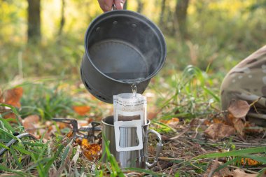 Adam yürüyüş yaparken filtreli kahve hazırlıyor. Sonbahar görünümü