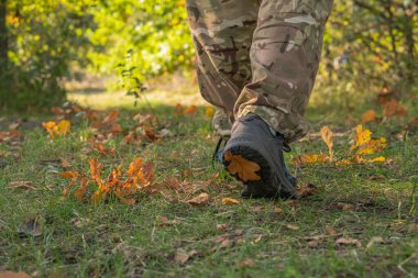 Adam sonbahar çimlerinde spor ayakkabıları giyer ve gider.