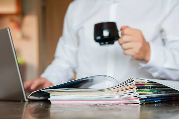 Manajer Melihat Majalah Dan Laptop Latar Depan Adalah Majalah Majalah — Stok Foto