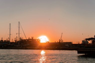 Endüstriyel Karadeniz limanı Odesa, Ukrayna Güzel turuncu günbatımında bir sürü vinç, kulübe, kutu ve tanklarla