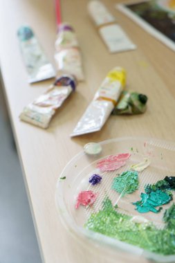 Ressam donatımı yağ renkleri dağınık çalışma alanında yatıyor
