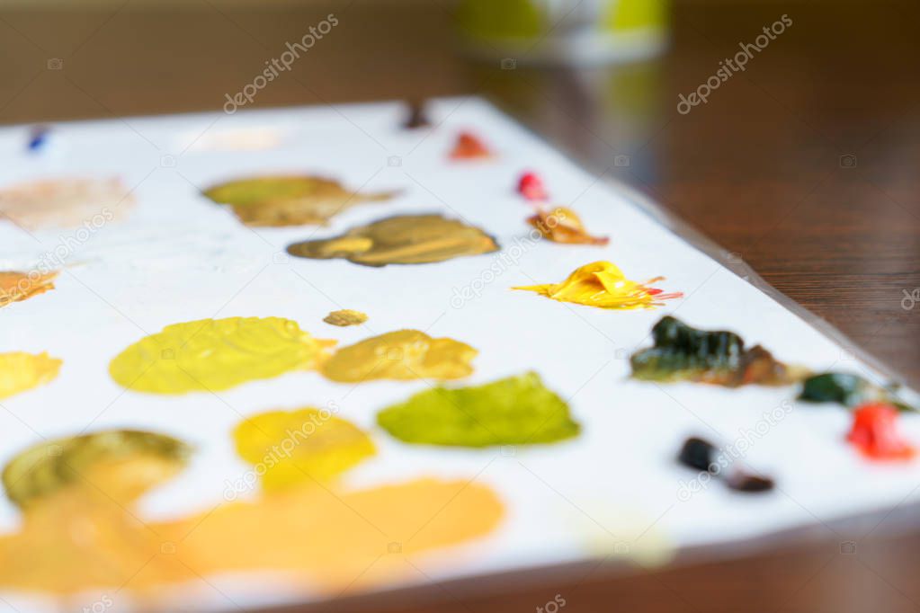 palette with oil paints with yellow-green shades