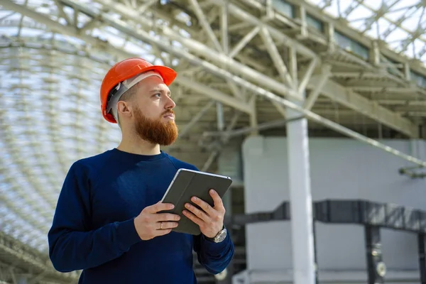 A man in a helmet in a large space with a tablet