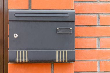 Kırmızı tuğla duvarına siyah posta kutusu.