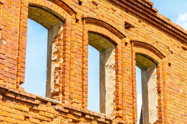 Büyük harap olmuş kırmızı tuğladan bir ev, beyaz bulutlu mavi gökyüzüne karşı..