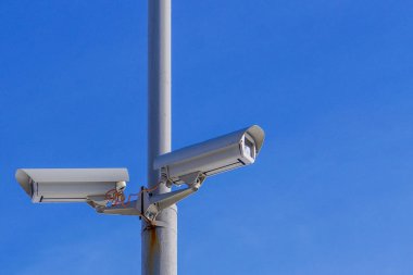 Mavi gökyüzüne karşı iki güvenlik kamera izleme.