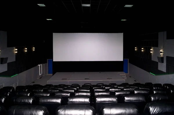 The interior of a cinema hall with black leather seats and a whi — Stock Photo, Image