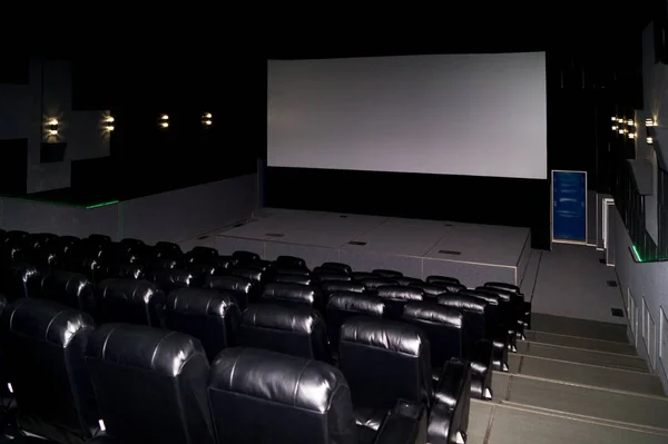 The interior of a cinema hall with black leather seats and a whi — Stock Photo, Image