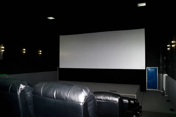 The interior of a cinema hall with black leather seats and a whi — Stock Photo, Image