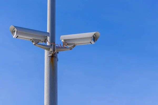 Duas câmaras de segurança contra o céu azul estão a monitorizar . Fotos De Bancos De Imagens Sem Royalties