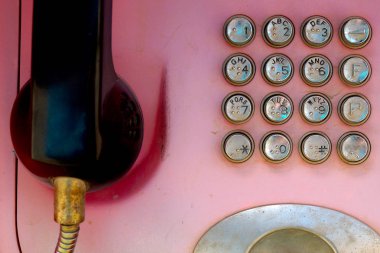 Metal düğmeli eski soluk kırmızı telefon. Kentsel iletişim teknolojileri.